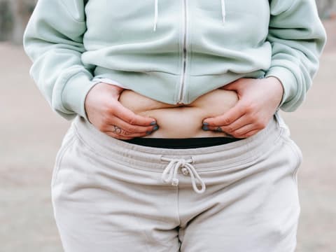 Adipöse Frau greift Bauchfett