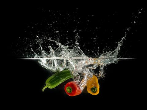 Drei Paprikaschoten fallen ins Wasser
