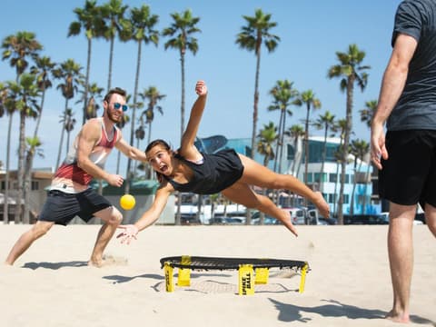 Menschen spielen am Strand Spikeball