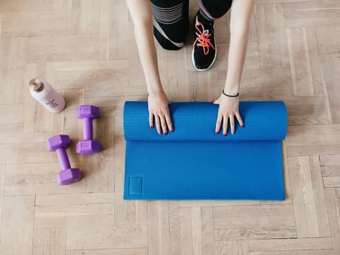 Frau rollt ihre Yogamatte zusammen