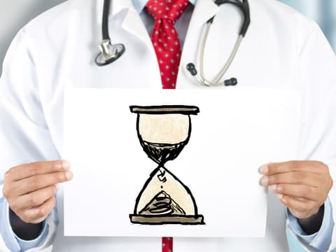 Arzt hält Grafik einer Sanduhr in den Händen