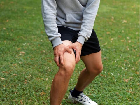 Mann greift sich vor Schmerzen ans Knie