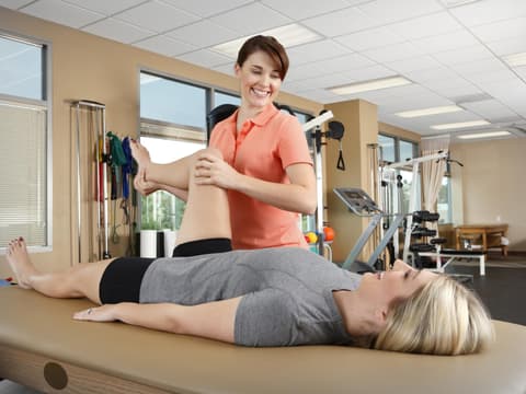 Physiotherapeutin behandelt das Bein einer Patientin