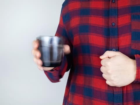 Person hält Glas in zitternder Hand