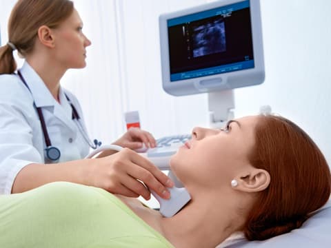 Ärztin untersucht die Schilddrüse einer Frau mittels Ultraschall