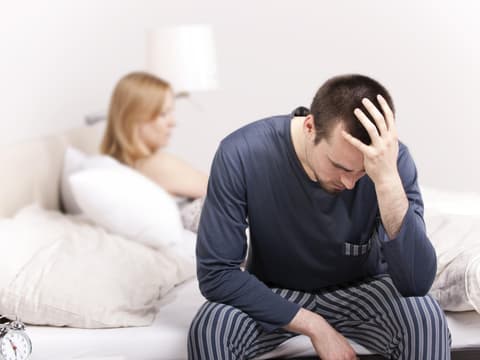 Mann sitzt auf Bett Scham