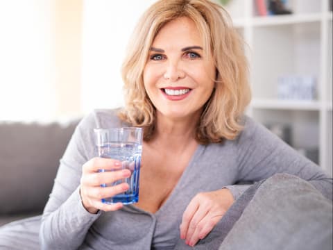 Lächelnde Frau mit Wasserglas in der Hand
