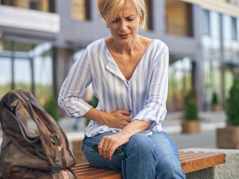 Frau mit Bauchschmerzen greift sich an den Bauch