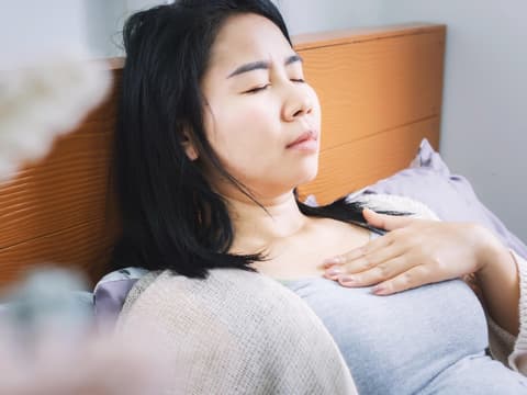 Frau im Bett mit Sodbrennen