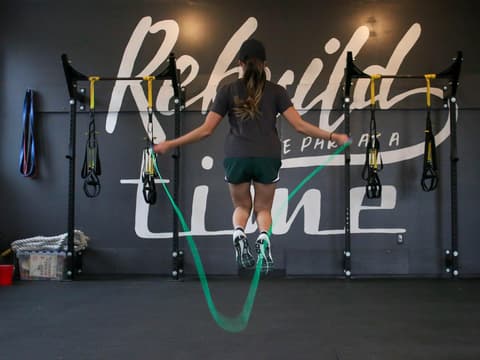Frau beim Springseilspringen mit grünem Seil im Gym