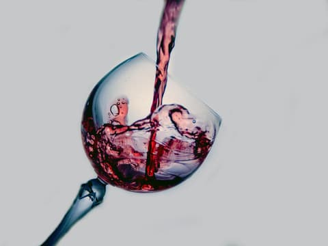 Weinglas wird mit Rotwein befüllt