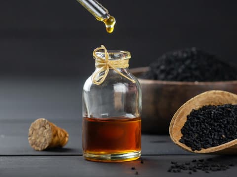 Schwarzkümmelöl und Schwarzkümmelsamen auf schwarzem Tisch