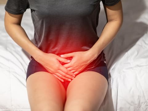 Frau hält Unterleib in Schmerzen