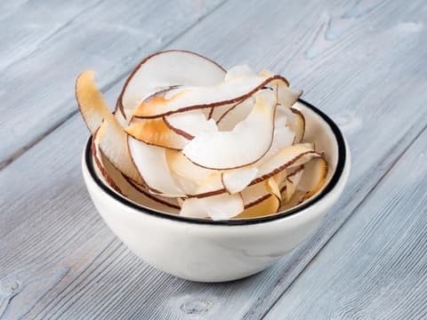 Kokoschips in weißer Schale auf Holzuntergrund