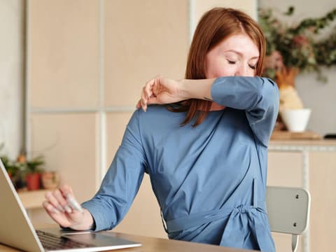 Frau hustet in Armbeuge