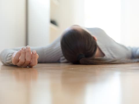 Frau liegt ohnmächtig auf dem Boden