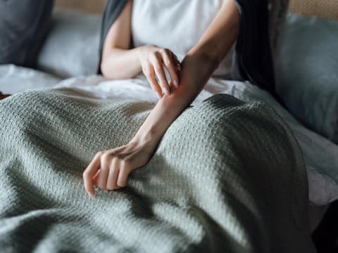 Frau mit juckendem Ausschlag am Arm