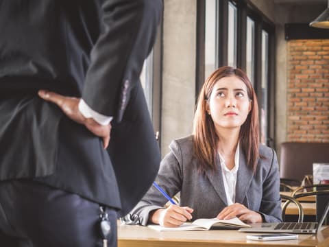 Junge Businessfrau schaut verunsichert auf Kollegen