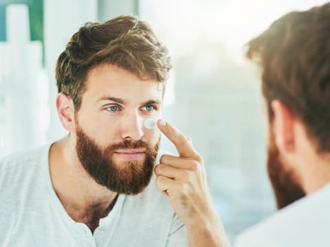 Mann pflegt Gesicht mit Creme
