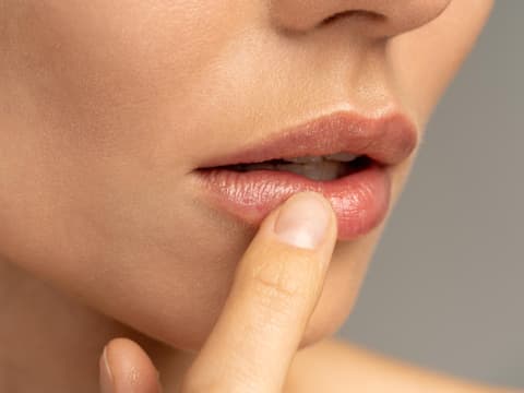 Frau berührt schmerzende Stelle an der Lippe