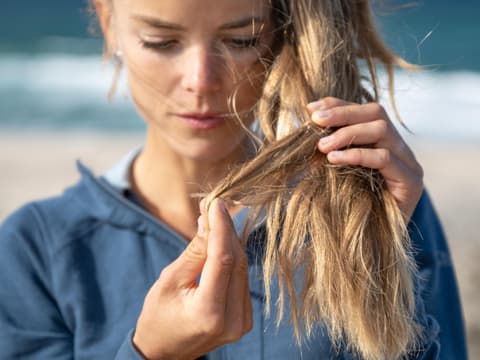 Frau beobachtet Spliss an den eigenen Haaren