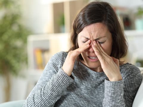 Frau fasst sich an schmerzende Augen
