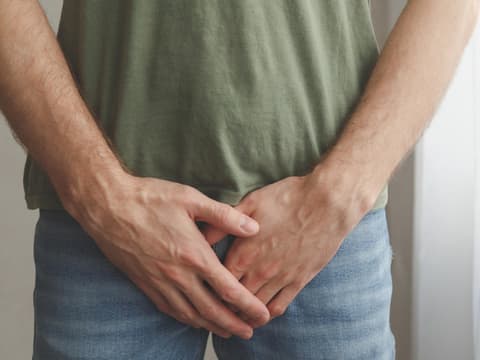 Mann hält Hand vor Schritt