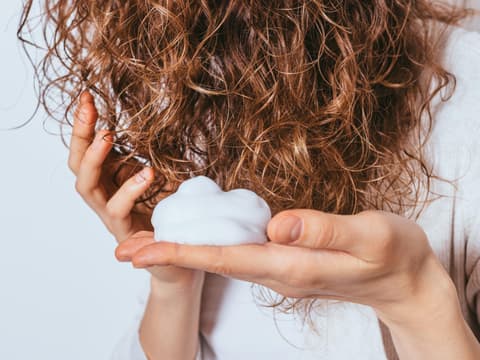 Frau massiert Schaum in Haare