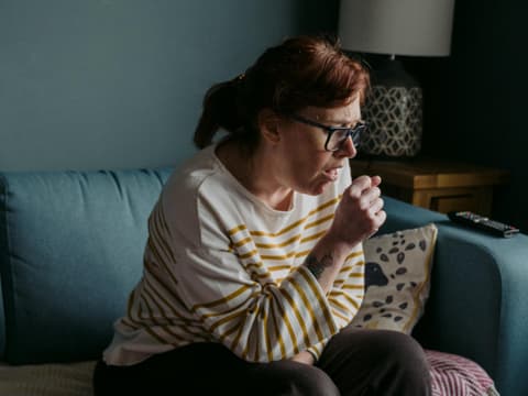Frau hustet auf Couch