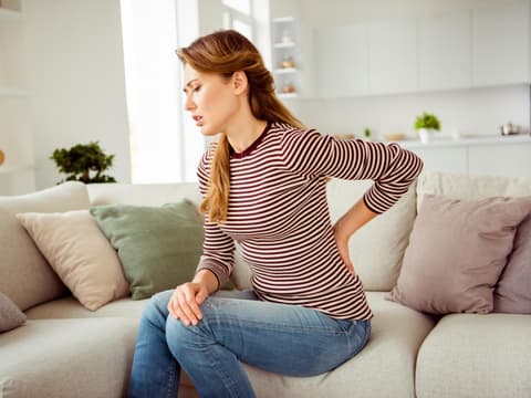 Frau hält sich den Rücken und hat Schmerzen