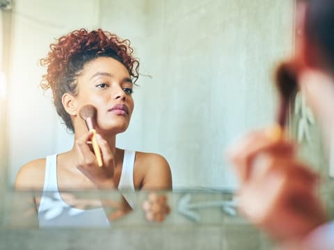 Frau trägt Make-up mit Pinsel auf