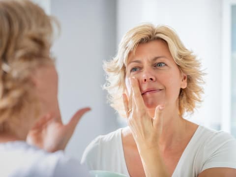 Frau cremt Gesicht ein