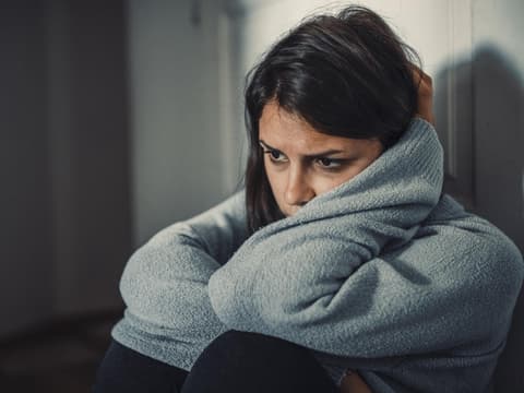 Frau sitzt bekümmert auf dem Boden