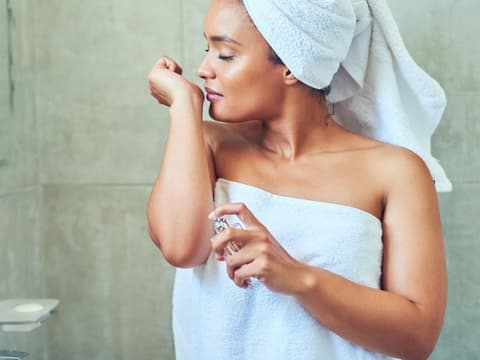 Frau riecht an Parfum nach Dusche