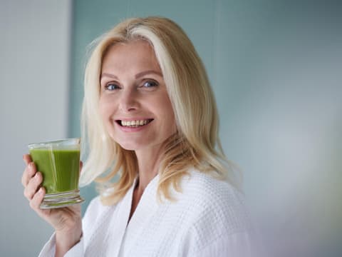 Ältere Frau hält Smoothie in der Hand 