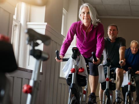 Frau mit grauen Haaren nimmt an Spinning-Kurs teil