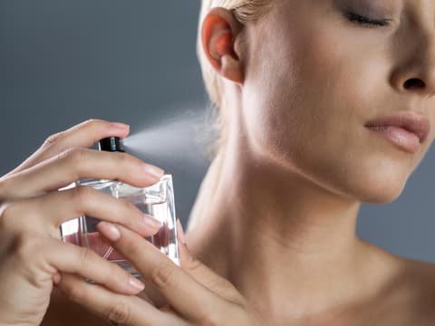 Frau sprüht Parfum auf ihren Hals