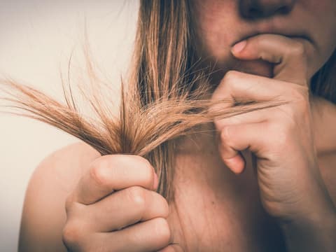 Frau prüft ihre Haarspitzen mit kritischem Blick