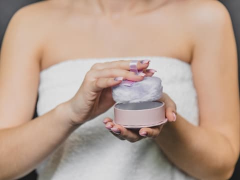 Frau trägt Puder mit Quast auf
