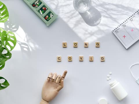 Top-Ansicht von Scrabblesteinen, die Long-Covid buchstabieren