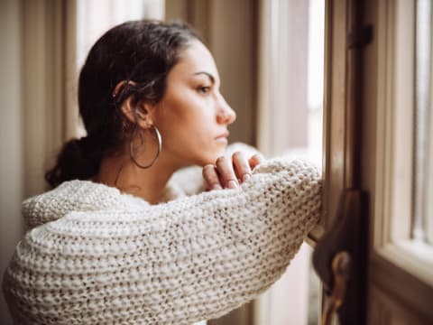 Frau schaut nachdenklich aus dem Fenster