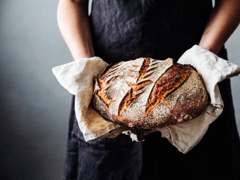 Bäckerin hält frisches Sauerteigbrot in den Händen