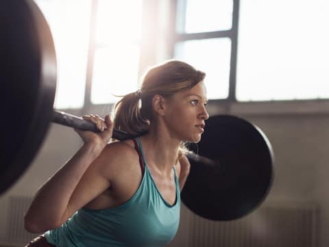 Frau macht Squats mit Langhantel