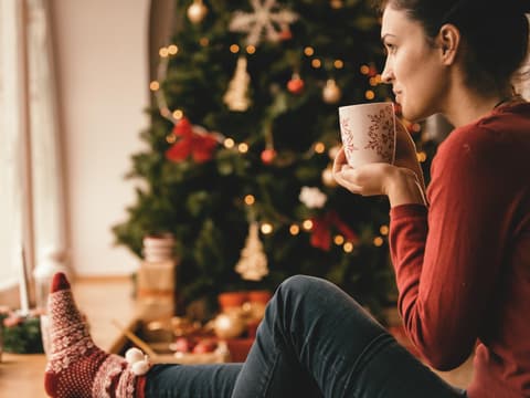 Frau mit Tee unter Weihnachtsbaum