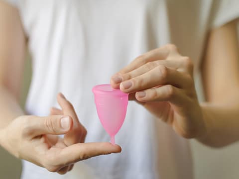 Frau hält Menstruationstasse in den Händen