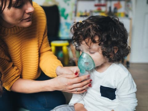 Mutter hilft Kind beim Inhalieren