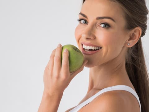 Lachende Frau mit Apfel