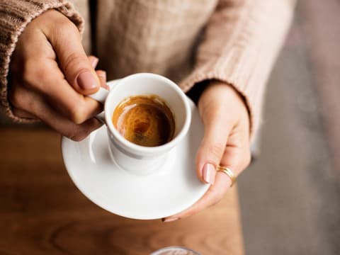 Frau hält Tasse mit Espresso in den Händen