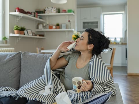 Frau auf Sofa mit Nasenspray