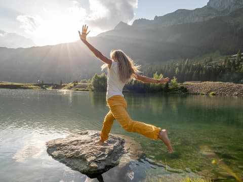 Frau springt über das Wasser und landet auf einem großen Stein